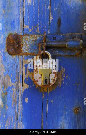 Weathered wooden blue door with metal padlock Stock Photo
