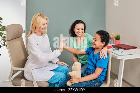 Child psychologist gives five an African American boy during a psychotherapy session Stock Photo