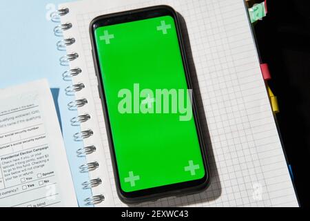 Mobile phone with green screen over notepad with warks and 1040 tax form Stock Photo