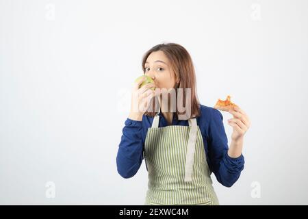 Adorable young girl in apron eating green apple instead of pizza Stock Photo