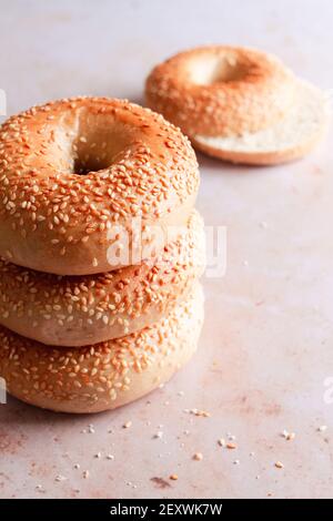 Stack of sesame seed bagels with one bagel cut in half in the background. Stock Photo