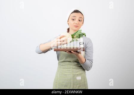 Young beautiful woman in apron looking at plate of cauliflower Stock Photo