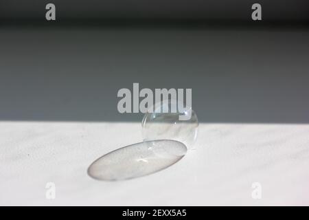 Soap bubble on the white table close-up. Contrasting shadow from a soap bubble.  Stock Photo