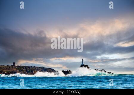 Image of Corbiere Lighthouse taken from the West with waves and moody cloudy sky, Jersey CI Stock Photo