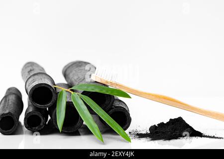 Bamboo activated charcoal, green leaf and toothbrush isolated on white background. Stock Photo