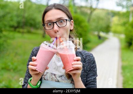 woman is drinking smoothies from two mugs Stock Photo