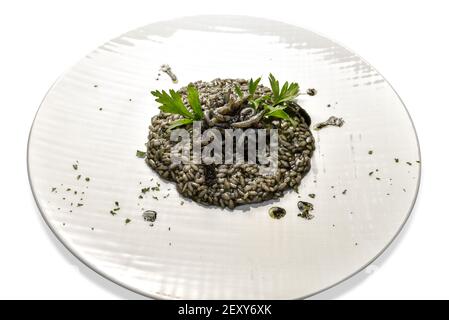 black risotto. rice with cuttlefish ink, seafood and parsley in white plate isolated on white Stock Photo