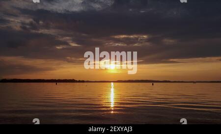 Beautiful golden sunset at the pond of lake Chiemsee with reflections in the water. Peaceful scene at the beach in summer Stock Photo