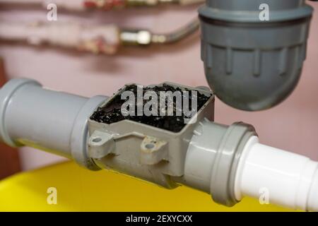Plumbing, kitchen check valve clogged, yellow basin and debris clogging up the pipe Stock Photo
