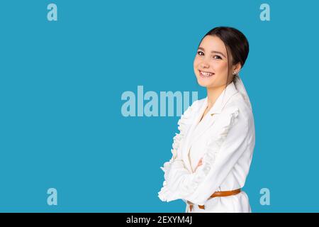 Young pretty businesswoman having break and dreaming in office wearing white suit , looking to camera on blue background with side space Stock Photo