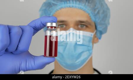 A young medic draws the Covid-19 vaccine from a flask into a syringe. Young handsome doctor prepares for Covid-19 vaccination, prepares a syringe with Stock Photo