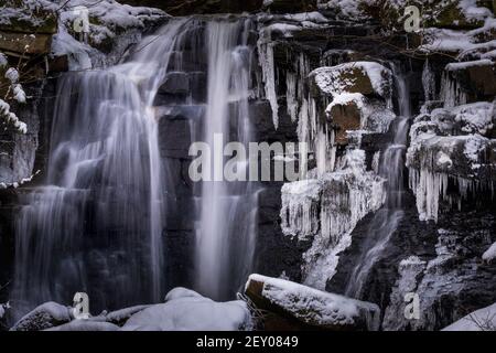 Frozen waterfall with ice covered rocks and icicles. Wharnley burn County Durham in winter. Stock Photo