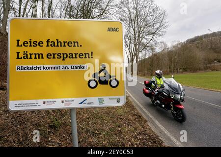 Montabaur, Germany. 05th Mar, 2021. A motorcyclist rides past a sign on the country road in the Gelbach valley asking bikers to ride quietly and considerately. Before the start of the season, the ADAC, supported by the state of Rhineland-Palatinate, is launching a pilot project against motorcycle noise. (to dpa 'Pilot project and further measures against motorcycle noise at the start of the season') Credit: Thomas Frey/dpa/Alamy Live News Stock Photo