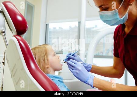 Pediatric dentist examining little girls teeth in the dentists chair Stock Photo