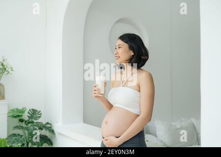 Young pregnant woman with glass of milk standing Stock Photo