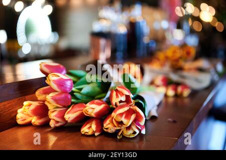A bouquet of red and yellow Tulips lies on the bar counter in the restaurant. International Women's Day Stock Photo