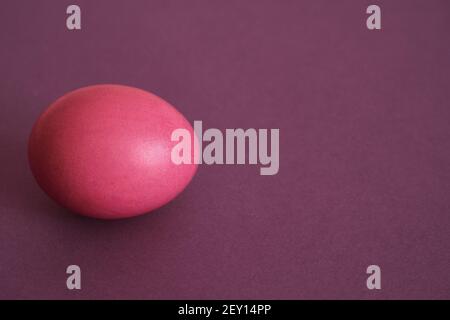 Painted pink egg on a violet background. Abstract composition. Top view. Easter holiday concept. Stock Photo