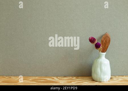 Vase of dry globe amaranth flowers on wooden table. Khaki gray background Stock Photo