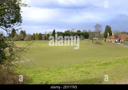 Loose Village, Kent, UK. 2 horses grazing in a paddock next to a converted oast house. Stock Photo