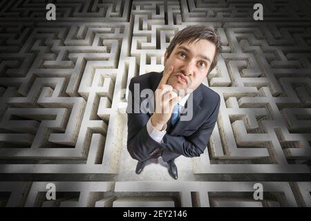 Young man is confused and lost in maze. 3D rendered illustration of maze. Stock Photo