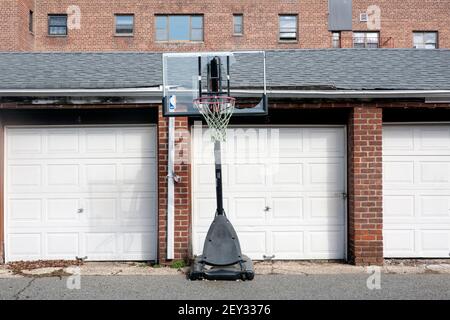 An outdoor basket & net in an alley way with several garages. In Bayside Queens, New York City. Stock Photo
