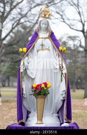 A statue of the Virgin Mary with a pupple cape signifying lent. At an outdoor prayer service in Flushing Meadows Corona Park in Queens, New York City.