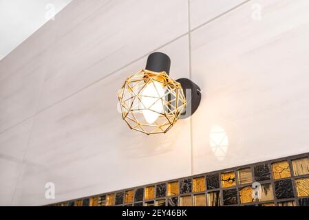 Classic yellow light bulb attached to the wall with ceramic tiles in the bathroom. Stock Photo