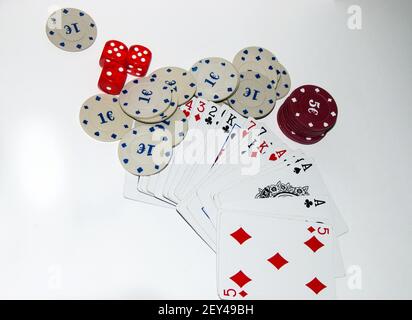 A top view of poker chips, playing cards, and dice on the white surface Stock Photo