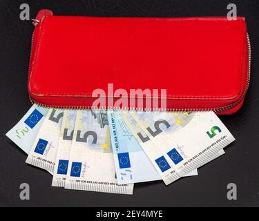 Close up of bundles of euro banknotes and opening a red wallet on a dark background. Selective focus. Stock Photo