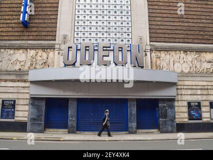 A couple wearing protective face masks walk past the closed Odeon cinema in Covent Garden during the third national coronavirus lockdown. London, United Kingdom 5 March 2021. Stock Photo