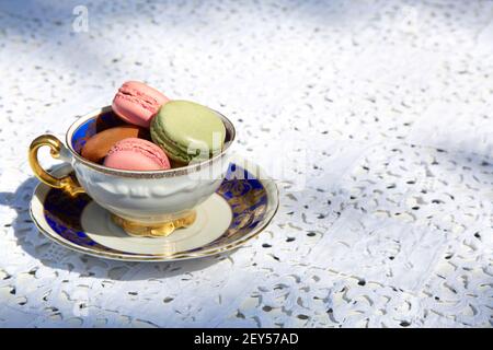 Macarons biscuits with ceramic cup with blue and golden decorations Stock Photo