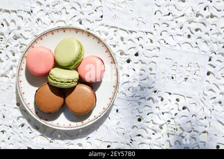 Macarons cookies in pink, green and brown colors with ceramic saucer, top view Stock Photo
