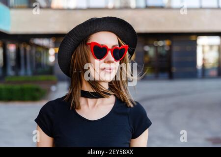 Portrait of pretty woman in black t-shirt and red skirt walking on the street Stock Photo