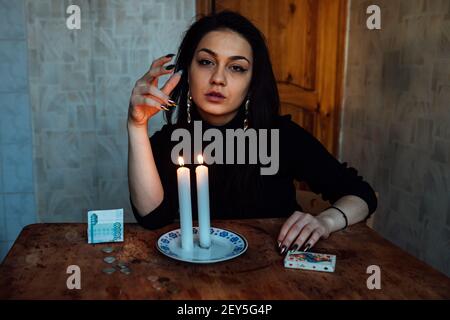 the girl is guessing on a lighted candle and cards, predicting the future and fate Stock Photo