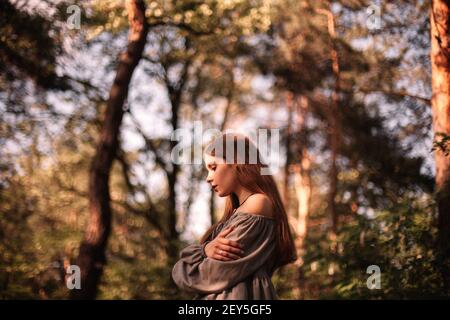 Side view of thoughtful teenage girl standing in forest during summer