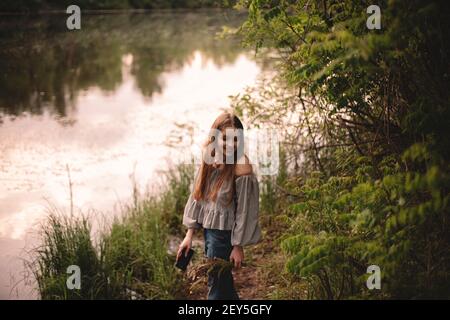 Happy teenage girl standing by river in forest during summer Stock Photo