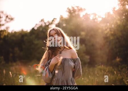 Young woman holding bouquet of dried flowers standing on summer field Stock Photo