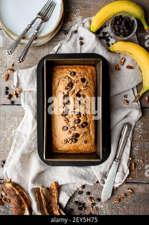 Overhead view of freshly baked banana bread on wooden background. Stock Photo