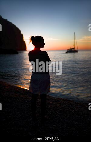 Silhouette of a contemplative young woman enjoying a beautiful sunset Stock Photo