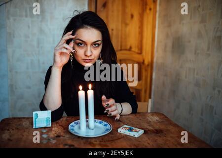 the girl is guessing on a lighted candle and cards, predicting the future and fate Stock Photo