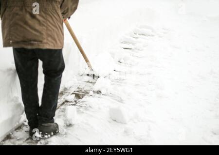 man removes snow from his yard after a snowstorm, shoveling snow Stock Photo