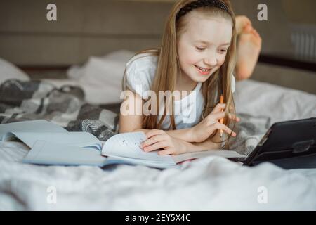 girl lying on the bed surrounded by notebooks Stock Photo