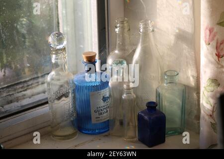 Blue and clear vintage bottles in a window with rainbows of light Stock Photo