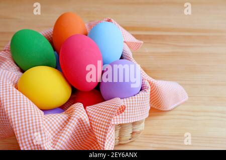 Basket Full of Multi-colored Easter Eggs Isolated on Wooden Table Stock Photo
