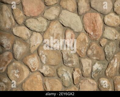 oddly shaped rocks or stones pieced and cemented together for home exterior support wall rocks fitting together like puzzle pieces by mason or masonry Stock Photo