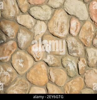 oddly shaped rocks or stones pieced and cemented together for home exterior support wall rocks fitting together like puzzle pieces by mason or masonry Stock Photo