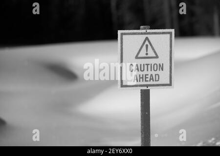 caution ahead sign triangle with exclamation mark in black and white snow in background cautioning thin ice ahead on  pond on golf course in winter Stock Photo