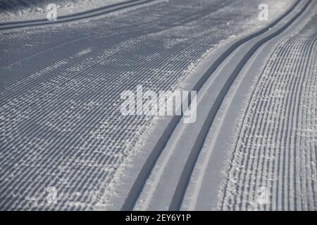 freshly groomed cross country ski tracks or nordic ski trail snow grooves for skis groomed trail leading away outside on winter day winter activity Stock Photo