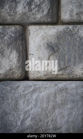 man made stones or rocks shaped like bricks close up of rock stone brick wall stacked together building exterior or landscaping vertical background Stock Photo