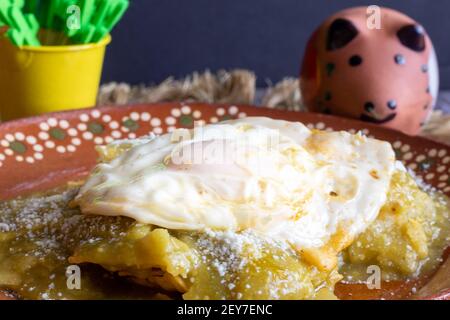 Mexican food. Green chilaquiles with over medium eggs, with sour cream and cheese Stock Photo